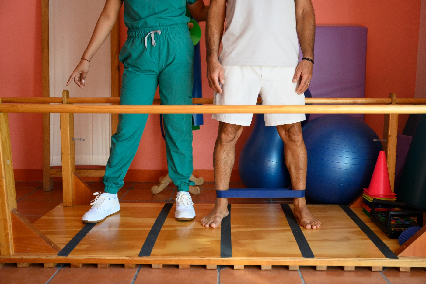 Therapist supporting a patient with balance and gait training between parallel bars during functional rehabilitation